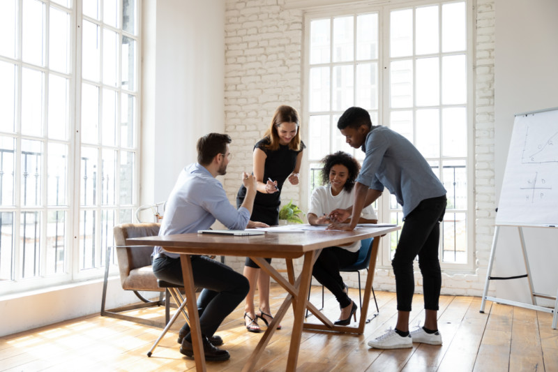 Motivated young diverse teammates working on project in office.